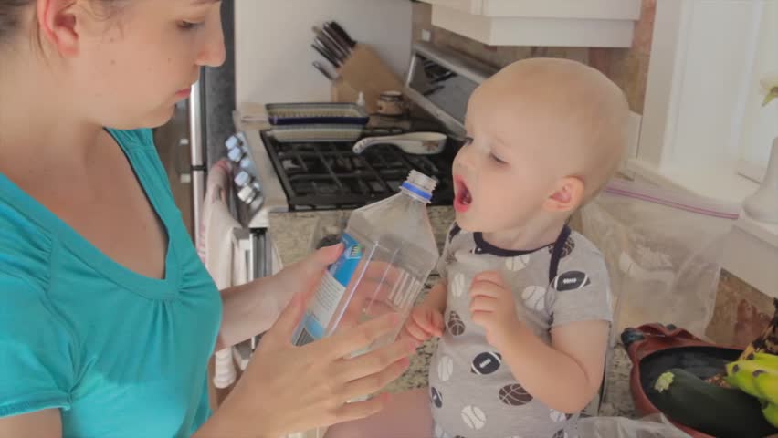 A mother giving her baby boy a drink of water