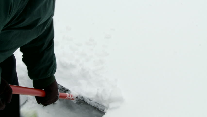 Handheld view of shoveling snow to clear a path