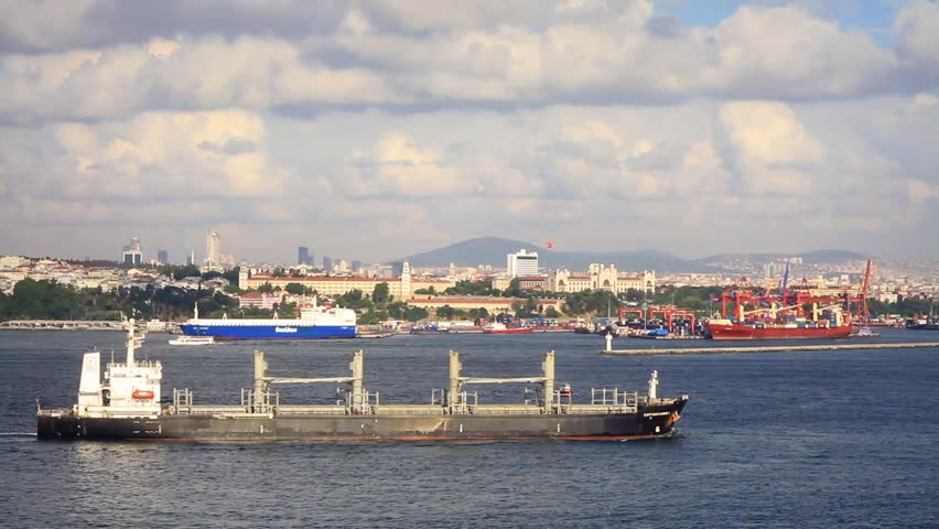 Cargo ship with deck cranes sailing in front of Istanbul container port
