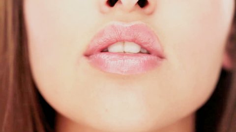 Closeup of the lips of a sensual woman giving a shushing gesture raising her finger to her lips as she asks for silence