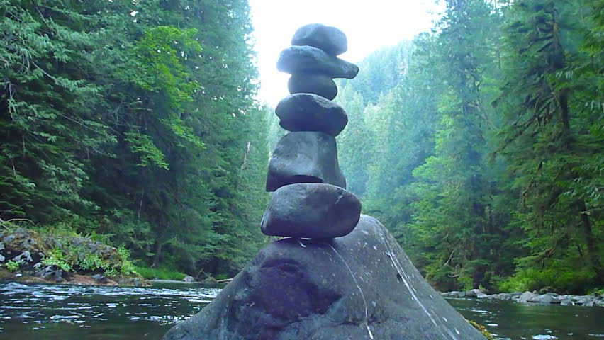 Lush wilderness river in Oregon with stones stacked on top of each other.