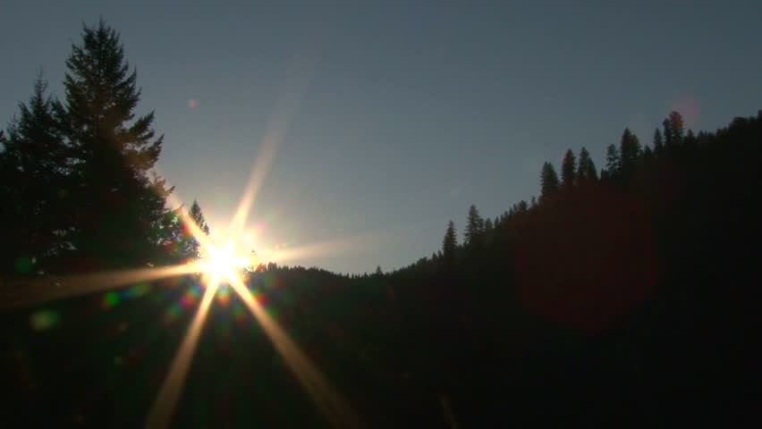 Time lapse of sun setting behind tree line in Idaho wilderness.