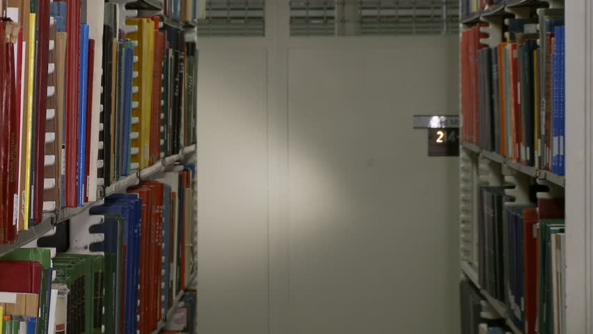 Close up of woman finding an orange book on library shelves.