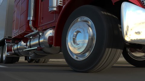 18 Wheel Truck on the road with sunset in the background. Large delivery truck is moving towards setting sun. Closeup on a moving wheel.