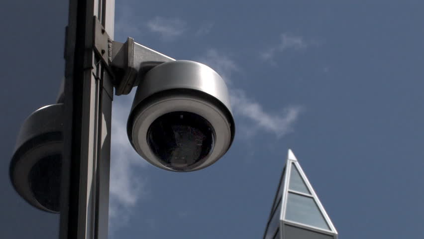 A surveillance camera on the side of an office building.