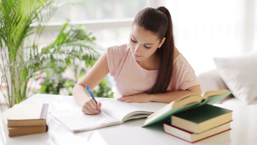 Student girl studying at table with books and smiling