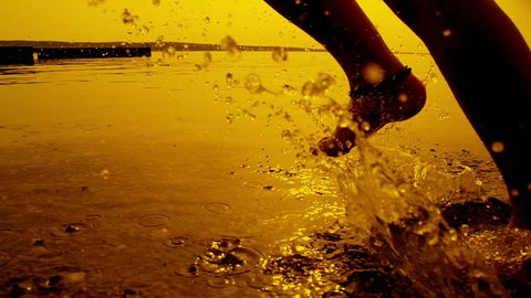 SLOW MOTION: Girl running in shallow water at sunset