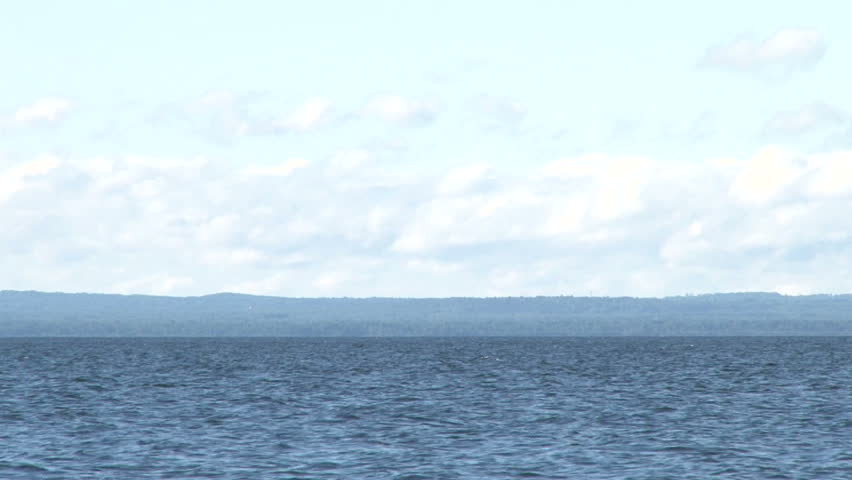 Lake Superior scenic on sunny, blue sky day with 1000 foot ore ship traveling through frame.