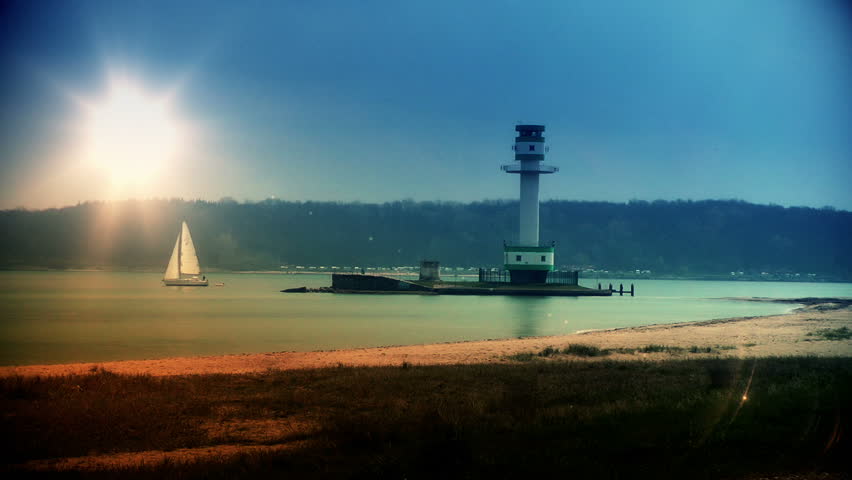 Lighthouse and boat sailing at sunset