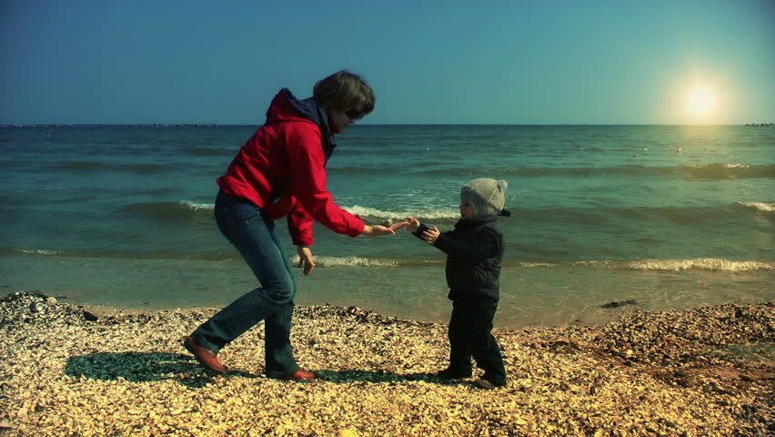 Mother and son throwing sea shells in water