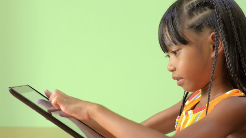 Profile view of a young Asian girl playing on a tablet pc.