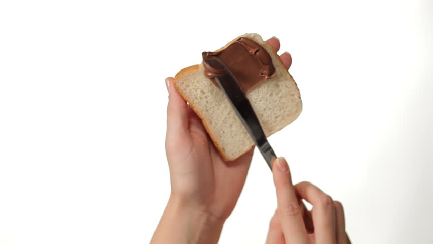 Hand Spreading Chocolate Cream on a Slice of Toast on white background