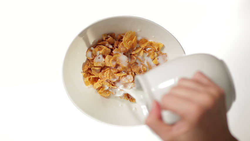 Hand Pouring Milk on Cornflakes on white background