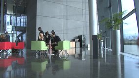 Large multi ethnic business group in relaxed meeting area of a large contemporary office building. High quality HD video footage
