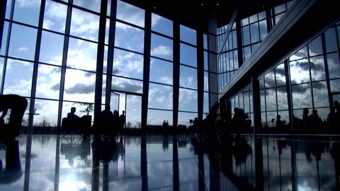 Time lapse with business group silhouetted in modern office building or airport - Clouds and business people rushing by. High quality HD video footage 