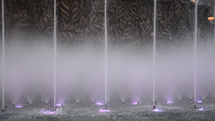Spray, splash and jet of water. Beautiful fountain of water dancing on lights