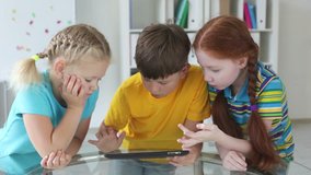 Modern kids using a touchpad sitting together