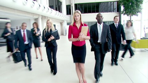 Large crowd of multi ethnic business people stride across a large contemporary corporate building. High quality HD video footage