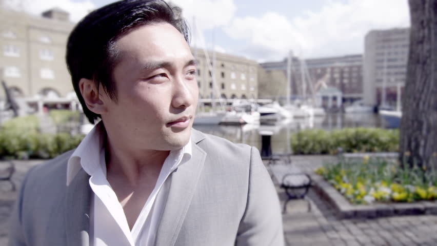 Portrait of a young handsome Asian man outdoors in the city