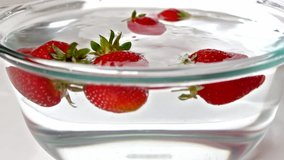 beautiful, red ,ripe strawberries falling into a bowl of water,video clip ; Strawberries in water
