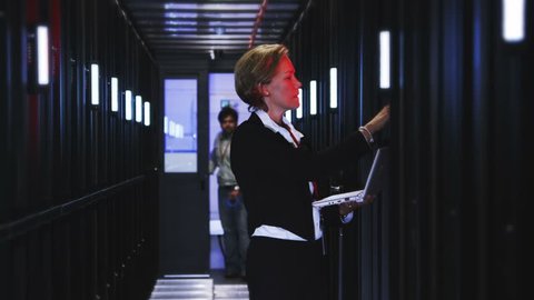 People working in computer server room data center. Walking along rows of super computers, racks and airconditioned cpu's.