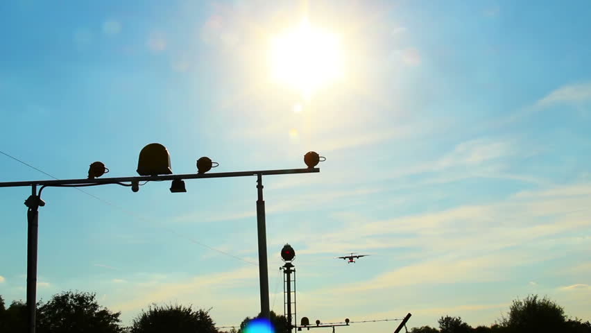 Flying aircraft at daytime silhouette through sun, landing light
