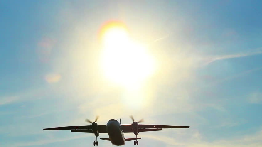 Airliner flies through sun rays at daytime, landing plane