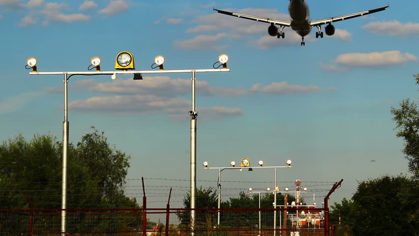 Landing aircraft with shadow above earth, landing light posts