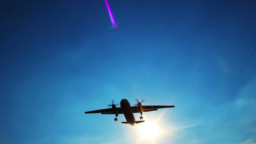 Large passenger airliner landing flying through sun rays