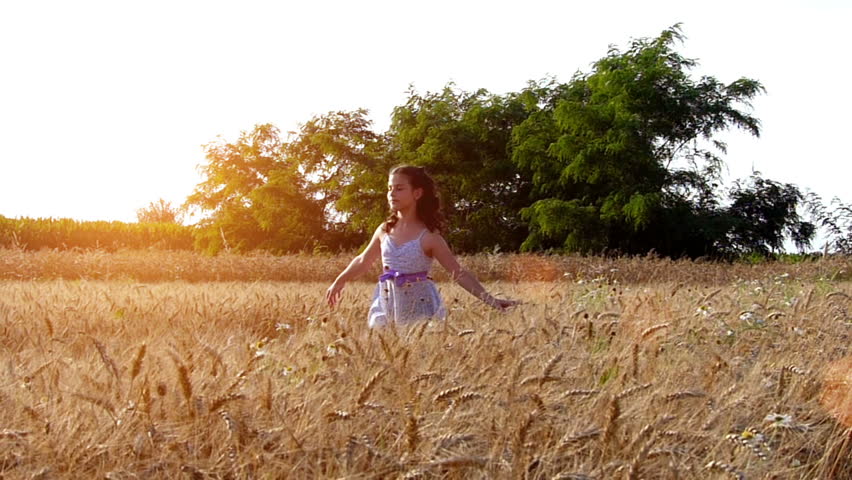 Little girl running cross the wheat field at sunset.High speed camera,slow motion.