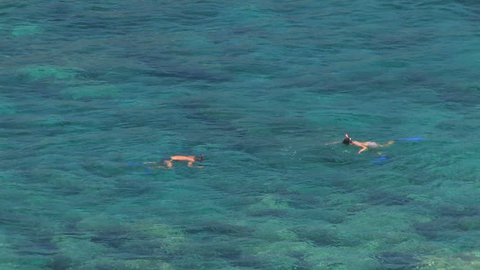 Two people snorkeling in turquoise ocean water