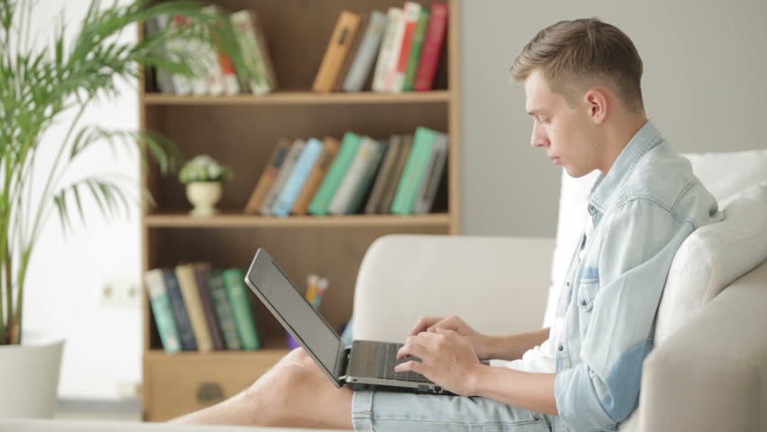 Young man sitting on sofa and using laptop