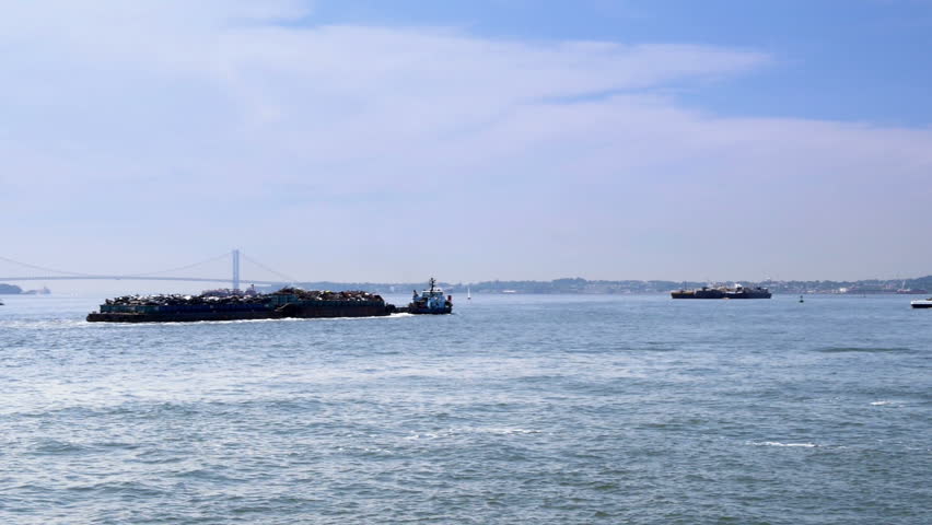 A scrap barge leaves New York.  The Verrazano-Narrows Bridge is seen in the
