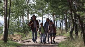 Cheerful parents and kids walking through summer forest