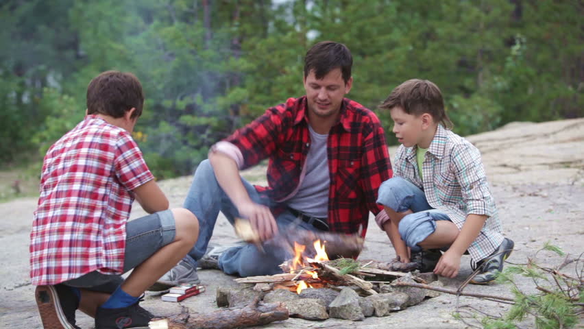 Father and sons getting warm at the camp fire
