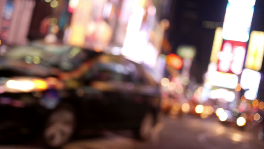 Defocused traffic and pedestrians in Times Square at night.