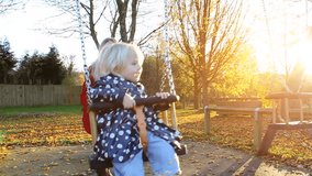 Mother and child at playground in the autumn sunshine. High quality HD video footage