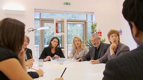 Diverse group of business people in a boardroom meeting, seated around a conference table. High quality HD video footage