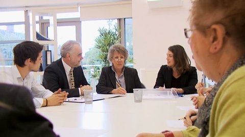 Diverse group of business people in a boardroom meeting, seated around a conference table. High quality HD video footage