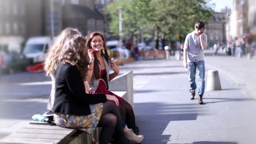 Friends talking out and about in the city. Teenagers spot a good looking boy.