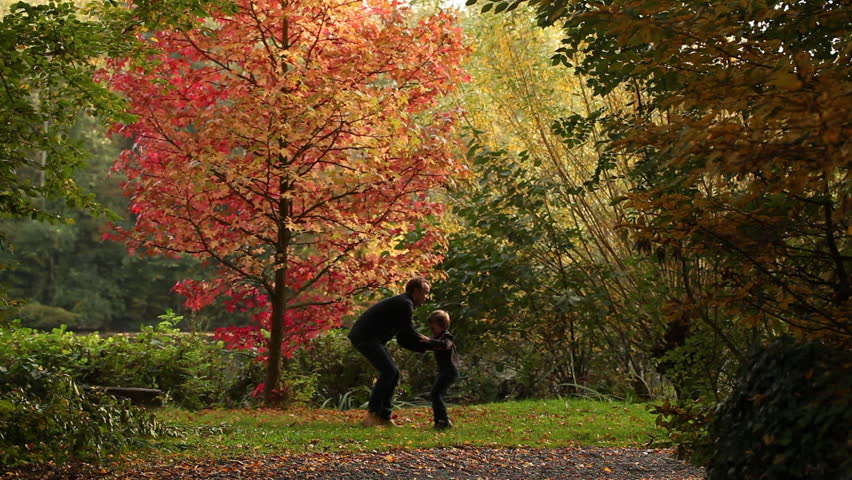 boy and his dad playing swinging game in the park, autumn