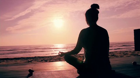 Meditation near the sea & doing yoga on a beach at sunrise