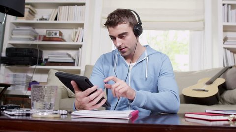 Young man with wireless digital tablet technology. Student house accommodation. Flat share with teenagers or young adults using digital tablets, laptops and cell phones.