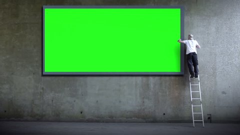 Billboard poster advertising. Green screen wall for copy space advertising. Man erects billboard. Part of a series of artistic clips I'm calling 'Wall Street'. Video de stock