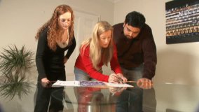 Planners and designers discuss plans over glass table - could be architects, engineers etc. High quality HD video footage