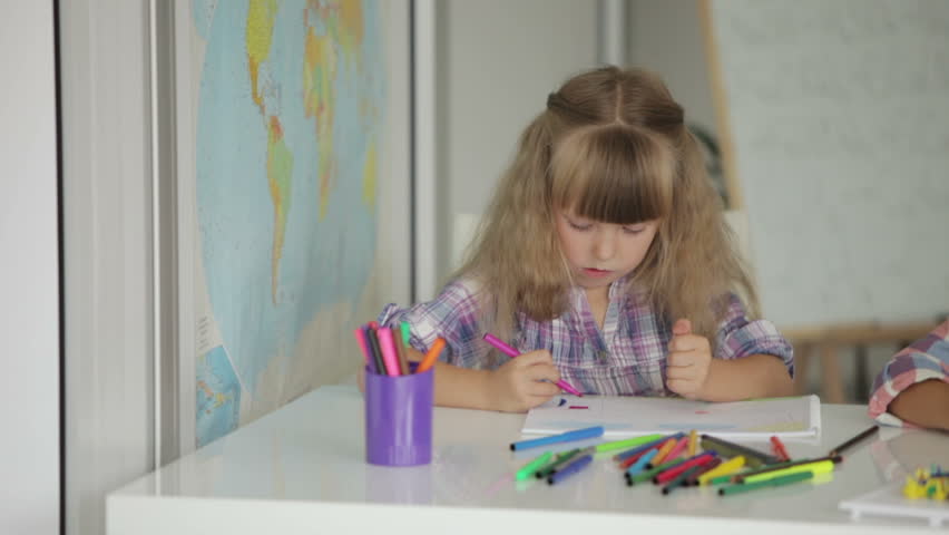 Two little girls drawing with colored pencils at drawing class and smiling at