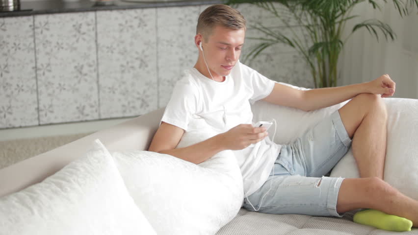 Handsome young man relaxing on with cellphone and listenning music