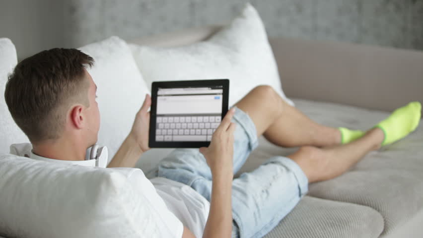 Student relaxing on sofa with tablet