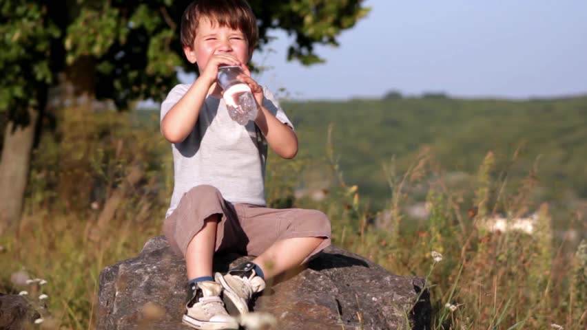 Boy drinkin mineral water from plastic bottle 