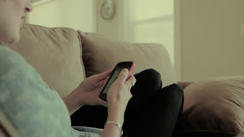 A woman texting while relaxing comfortably on her sofa